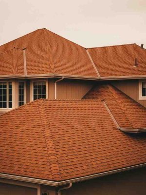 Two story suburban home with burnt orange architectural shingle roof installed by licensed roofing contractors in Fort Bend County